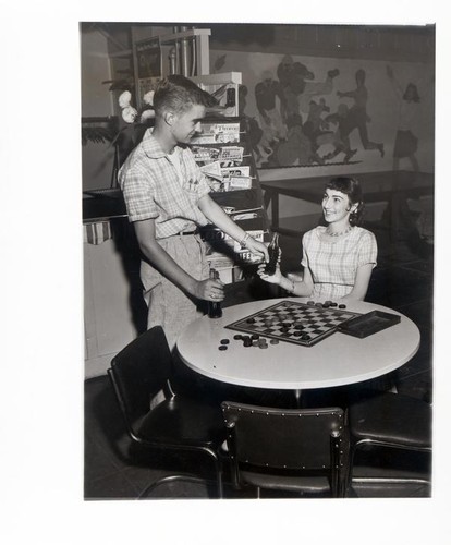 Teenage boy handing a bottled drink to a teenage girl