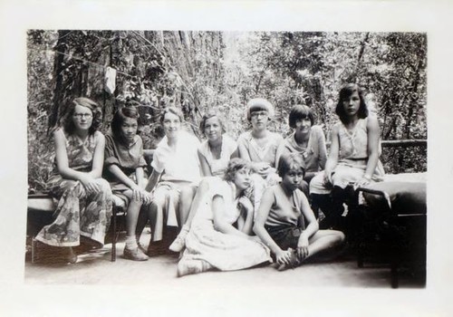 Girls sitting on cots in the forest