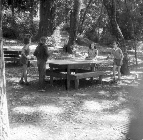 Four young teenage girls playing ping pong outdoors