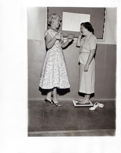 One woman being weighed by another from the YWCA's Ladies Be Slim Club