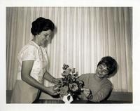 Photograph of women and a flower arrangement and a note identifying them