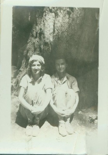 Two teenager girls sitting against a large boulder