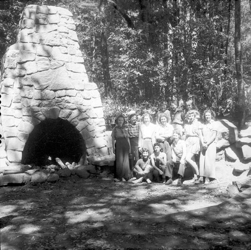 A group of young women posing by an outdoor stone hearth