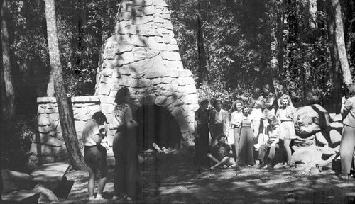 Group of women and teenage girls near a large outdoor stone hearth