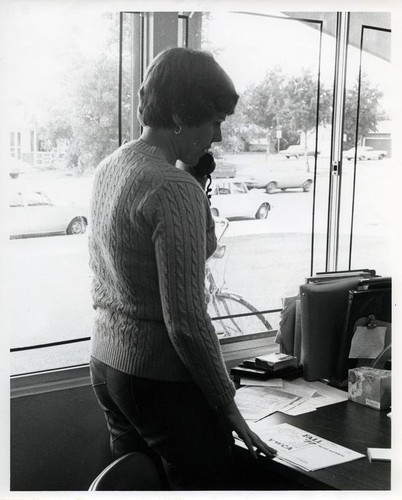 Woman standing at a desk and speaking on the telephone