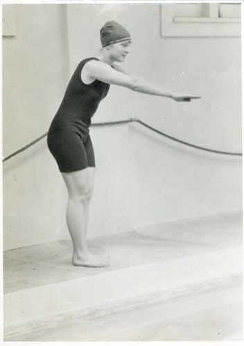 Young woman in a diving pose at the side of a pool