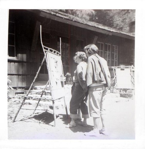 Women looking at a sign outside a building in the forest