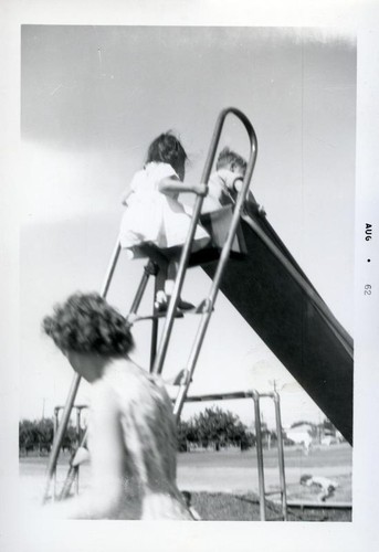 Two young children playing on a slide