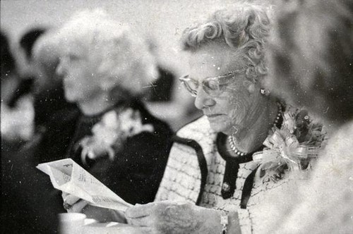 Woman with a corsage reading at a table