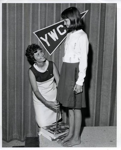 Susanne B. Wilson measures the hem of a girl's skirt