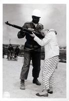 Photograph of a soldier helping a girl with a rifle and an explanatory note