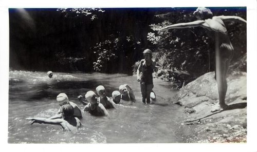 Instructor teaching a group of girls how to swim at a swimming hole