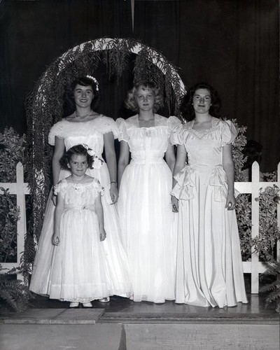 Teenage girls and a little girl dressed in long white formal dresses