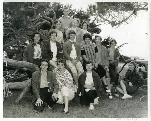 Group of teenage girls posing on and around a fallen Monterey pine tree