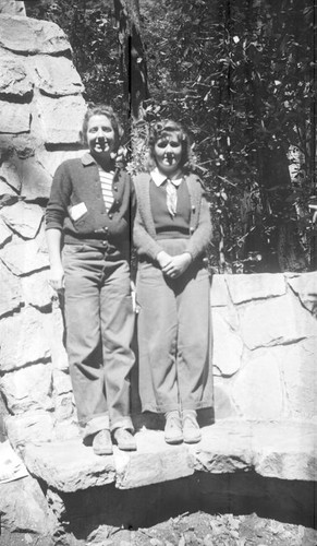 Teenage girls standing on a stone bench next to a hearth