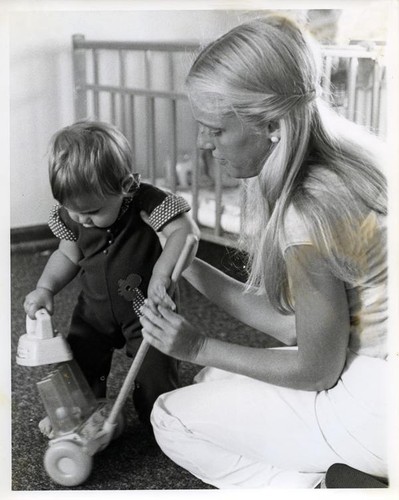 Teenage girl helps a toddler play with a toy