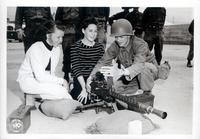 Photograph of a soldier and two girls with a machine gun and a descriptive note