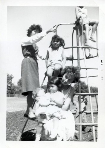 Young children and two teenager girls on a jungle gym