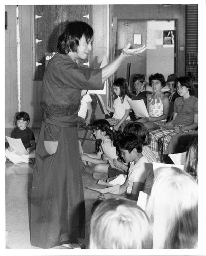 Adult male speaking to a group of children