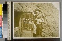 A Borax miner about to enter his home in an abandoned tunnel. Note the miner's candle in his right hand and the canteen of water by his left side