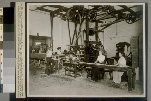 Soap Wrapping Room, Bayonne Refinery, showing automatic machine for wrapping soap. This machine wraps 115 cakes a minute. The girls place the soap in cases which are afterwards nailed up and sent down in the elevator in the background to the Shipping Room below