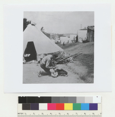 [Man cooking at outdoor kitchen. Unidentified refugee camp.]