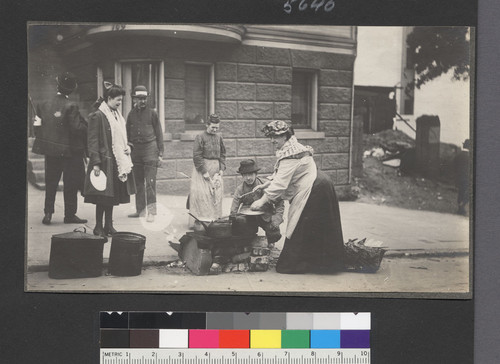 [Refugees at makeshift sidewalk kitchen.]