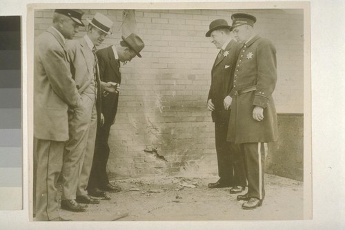 [Unidentified men, including police officers, inspect site of bomb explosion. Corner of Steuart and Market Streets, San Francisco. During Preparedness Day Parade, July 22, 1916.]