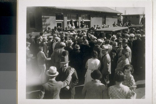 [Crowd gathering around taxis in front of building]