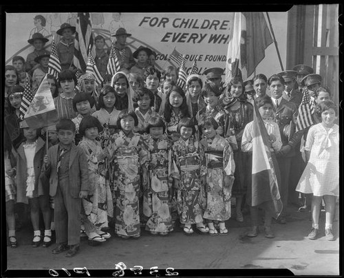 Children in ethnic dress posing with billboard advertising Golden Rule Week at Golden Rule Foundation Pageant, Los Angeles, 1930