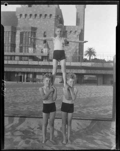 Identical triplet sons of politician George W. Neal playing on the beach with other children, Santa Monica, circa 1930's