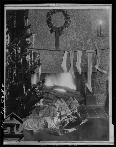 Montage photograph of Mawby triplets in front of fireplace with Christmas tree and stockings, [Santa Monica, 1929]