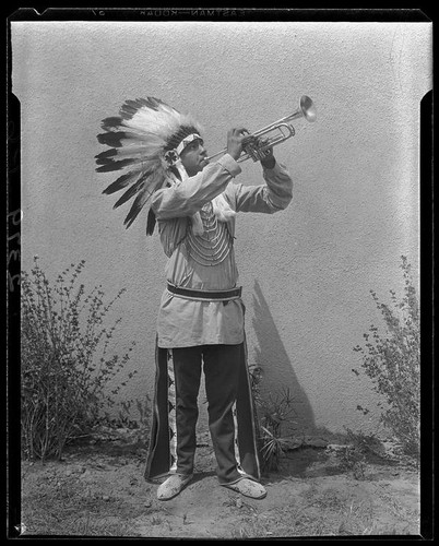 Young man in Indian regalia playing trumpet, 1928