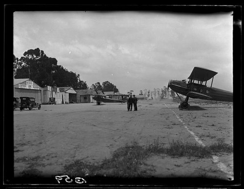 Biplane and men at airfield, [1920s?]