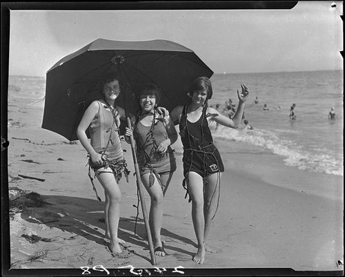 Young women posing on beach with umbrella and seaweed, Pacific Palisades, 1927