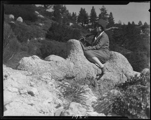 Mrs. Tom Carlisle seated on rock formation, Riverside County, [1920-1939?]