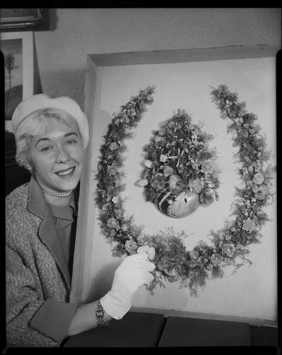 Dane Gorrell with 1888 horseshoe-shaped shell art wreath made by poet Ina Donna Coolbrith, Santa Monica, 1953