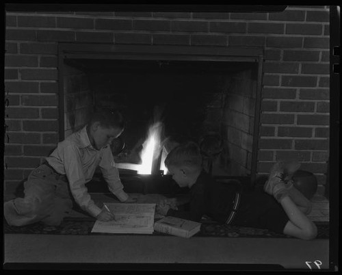 Boys writing in front of fireplace, Los Angeles, circa 1935