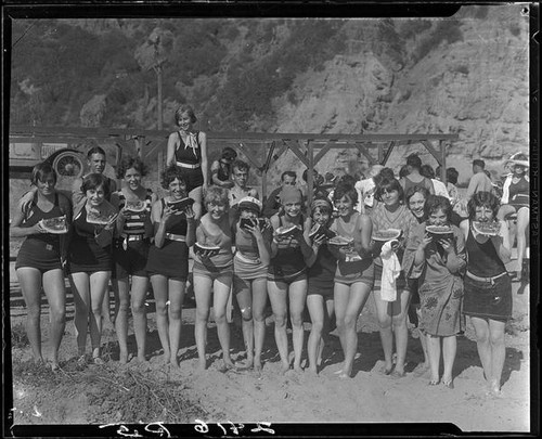 Young women on beach eating watermelon, Pacific Palisades, 1928