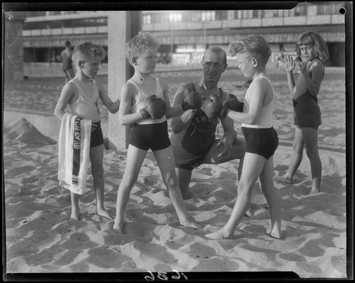 Identical triplet sons of politician George W. Neal playing on the beach with other children, Santa Monica, circa 1930's