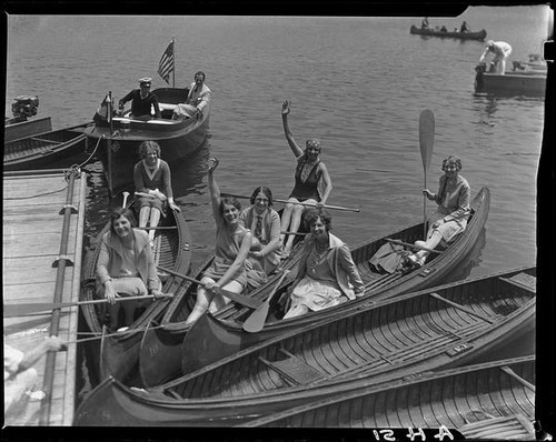 Women in canoes, men in motorboat, docked, Lake Arrowhead, 1929