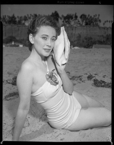 Betty Herrick [?] on beach with seashell, [1935-1955]