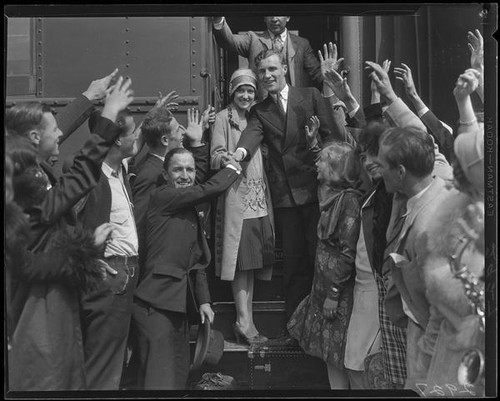 Crowd greeting or seeing off couple on train, [1928?]