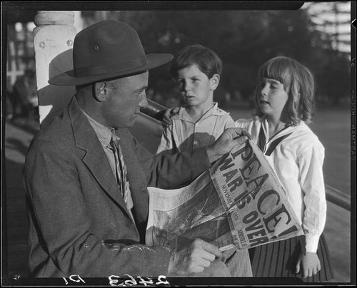 Veteran Leonard L. Deaver and two children with newspaper, Los Angeles, 1928 or 1930