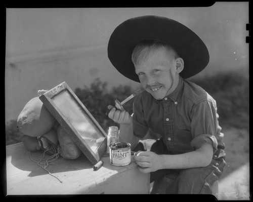 Boy painting beard and mustache on himself, Los Angeles, circa 1935