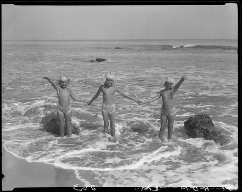 Mawby triplets wading in surf hand in hand, Malibu, 1928