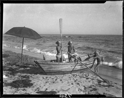 Mawby triplets playing in a rowboat on the beach, Malibu, 1928