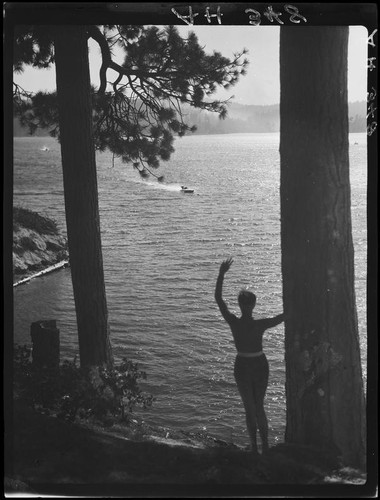 Woman waving at motorboat, Lake Arrowhead, 1929