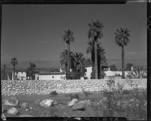 House with tiled roof with stone wall and palm trees, Palm Springs, [1930s or 1940s?]