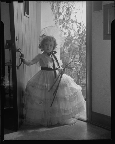 Helena Burnett in dress and bonnet holding lilies, 1947-1950